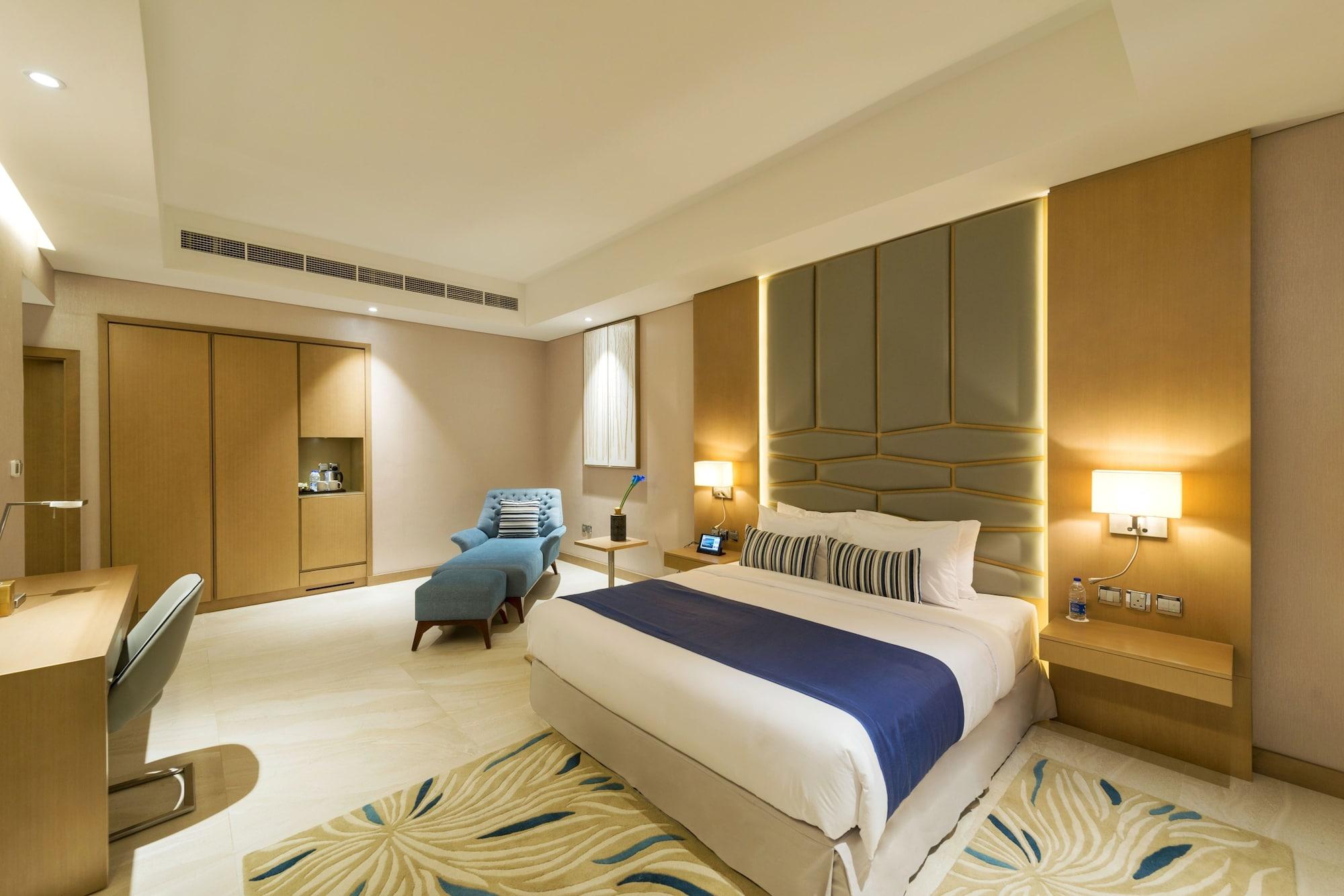 Canal Central Hotel Business Bay Dubai Exterior photo The photo shows a modern hotel room that appears to be well-designed and spacious. In the center, there is a comfortable bed with white linens and a blue accent blanket. A stylish headboard complements the bed. To the side, there is a lounge chair in