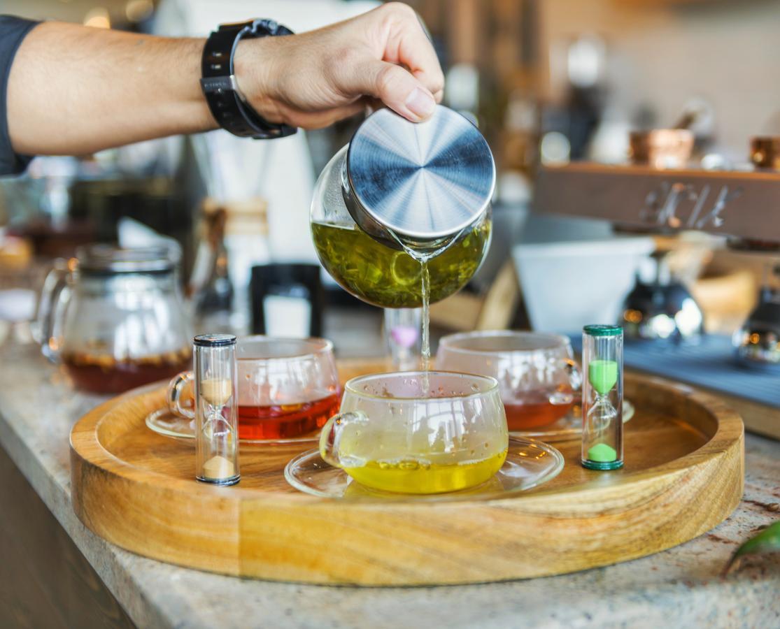 Canal Central Hotel Business Bay Dubai Exterior photo The photo shows a person pouring a liquid from a metallic container into a glass teacup. There are several glass teacups arranged on a wooden tray, each containing different colored liquids, likely various types of tea. Next to the cups, there are sm